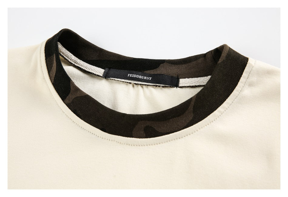 Close-up of the cream T-shirt's dark camouflage-patterned neckline and sewn-in label.