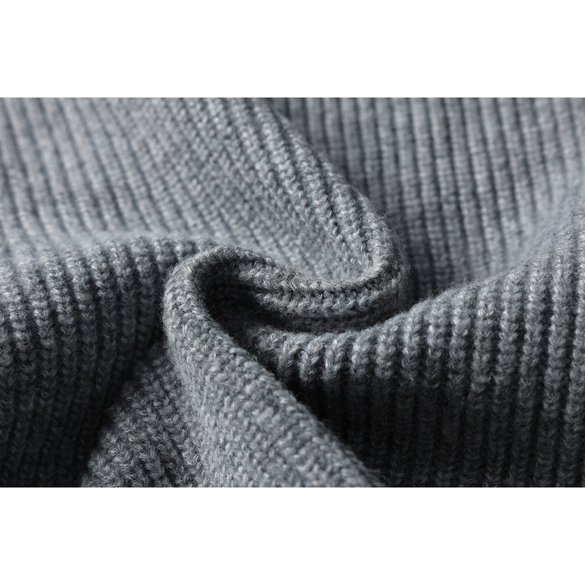 Macro view of the gray sweater's textured rib-knit fabric and folded edge.