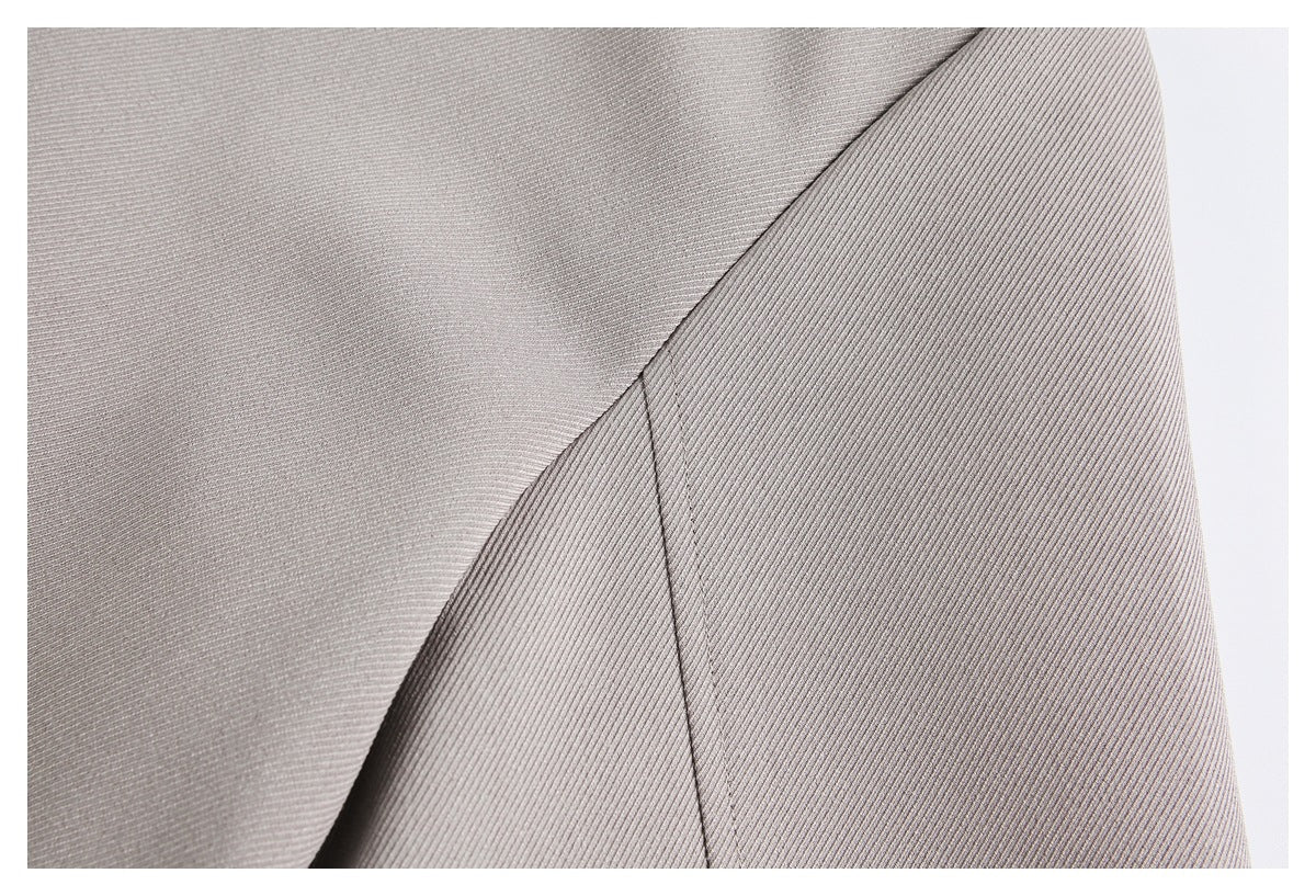 Close-up of light taupe-gray garment fabric showing a curved seam and fine diagonal texture.