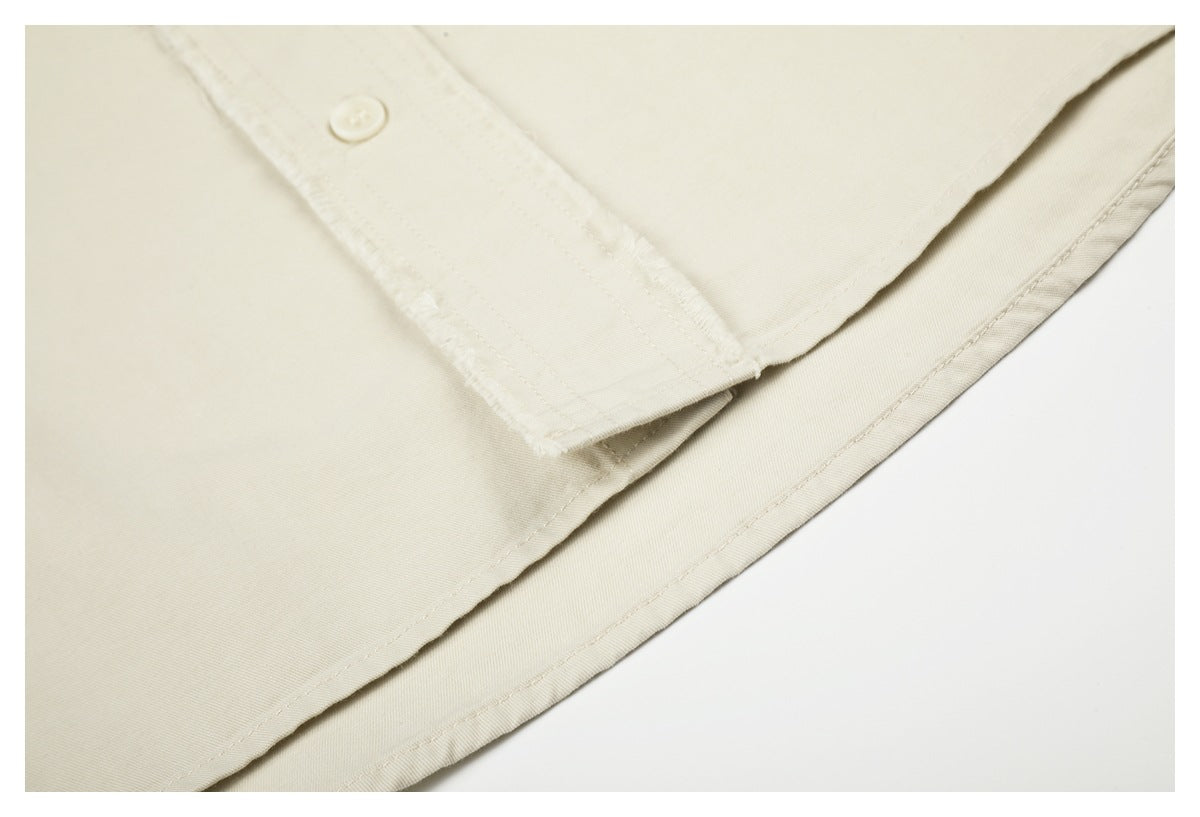 Close-up of the ivory shirt's button placket and curved stitched hem.