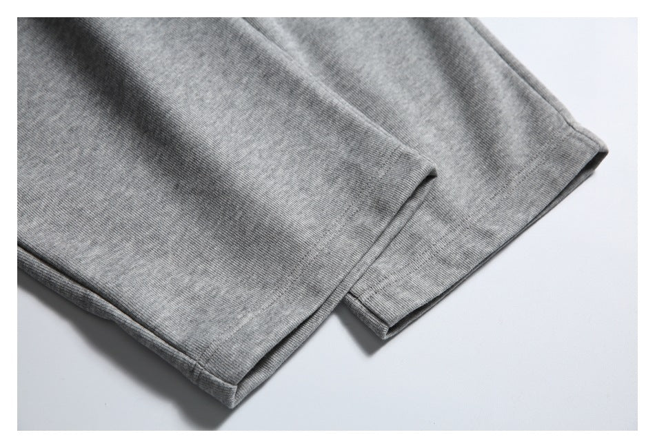 Close-up of the stitched hem on gray jogger pants laid flat.