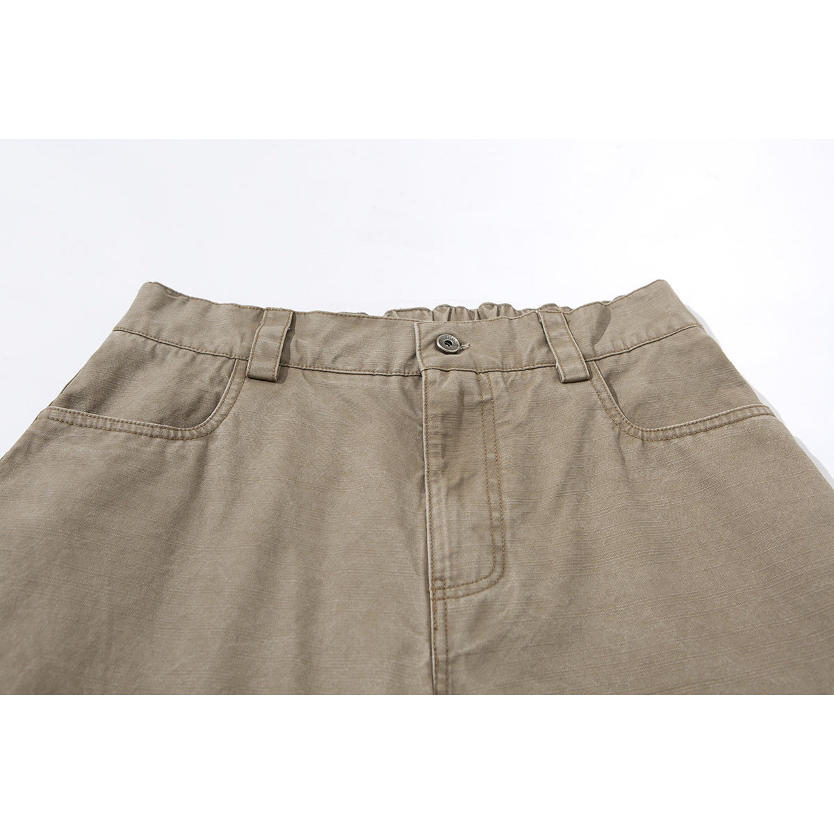 Close-up of tan cargo pants showing the waistband, belt loops, button, fly, and front pockets.