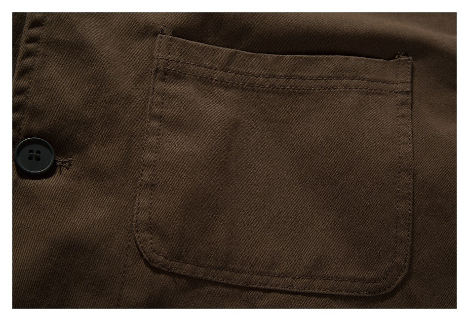 Close-up of a dark brown shirt's stitched chest pocket and a black button.
