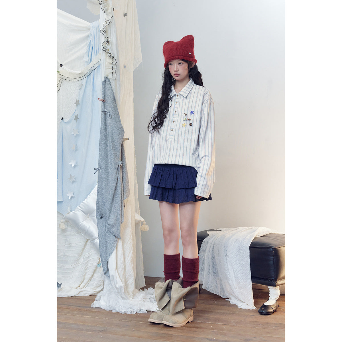 Full-length model wearing a striped white shirt, navy tiered skirt, red knit hat and leg warmers, and taupe boots.