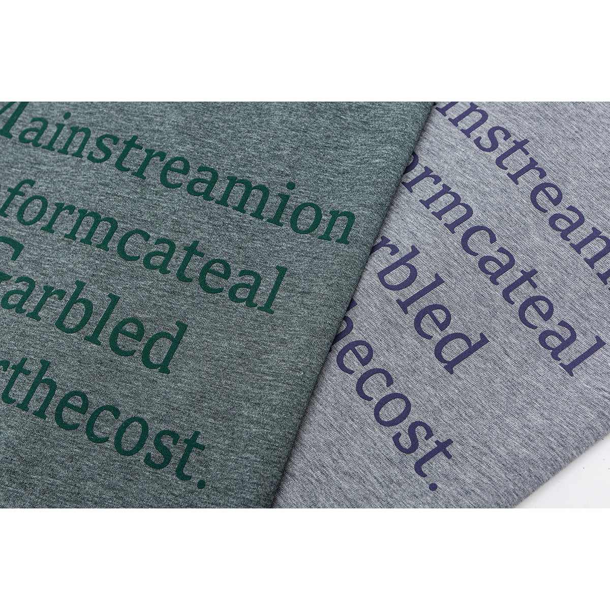 Close-up of green and light gray heathered shirts with large dark English text printed on them.