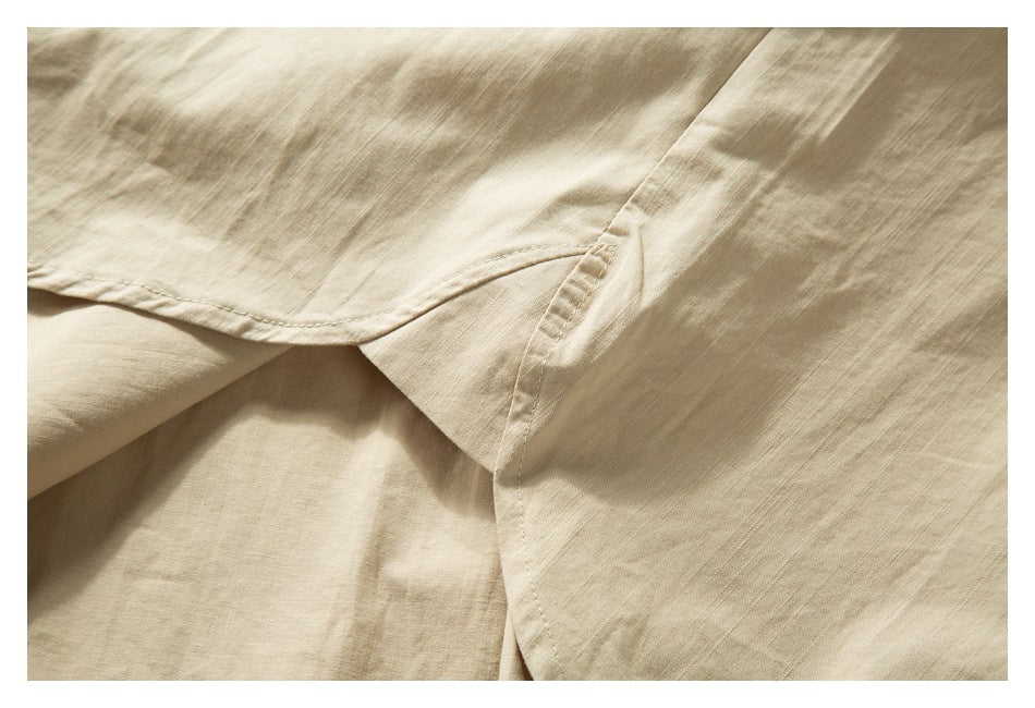 Close-up of a beige shirt seam and overlapping fabric at a side opening.