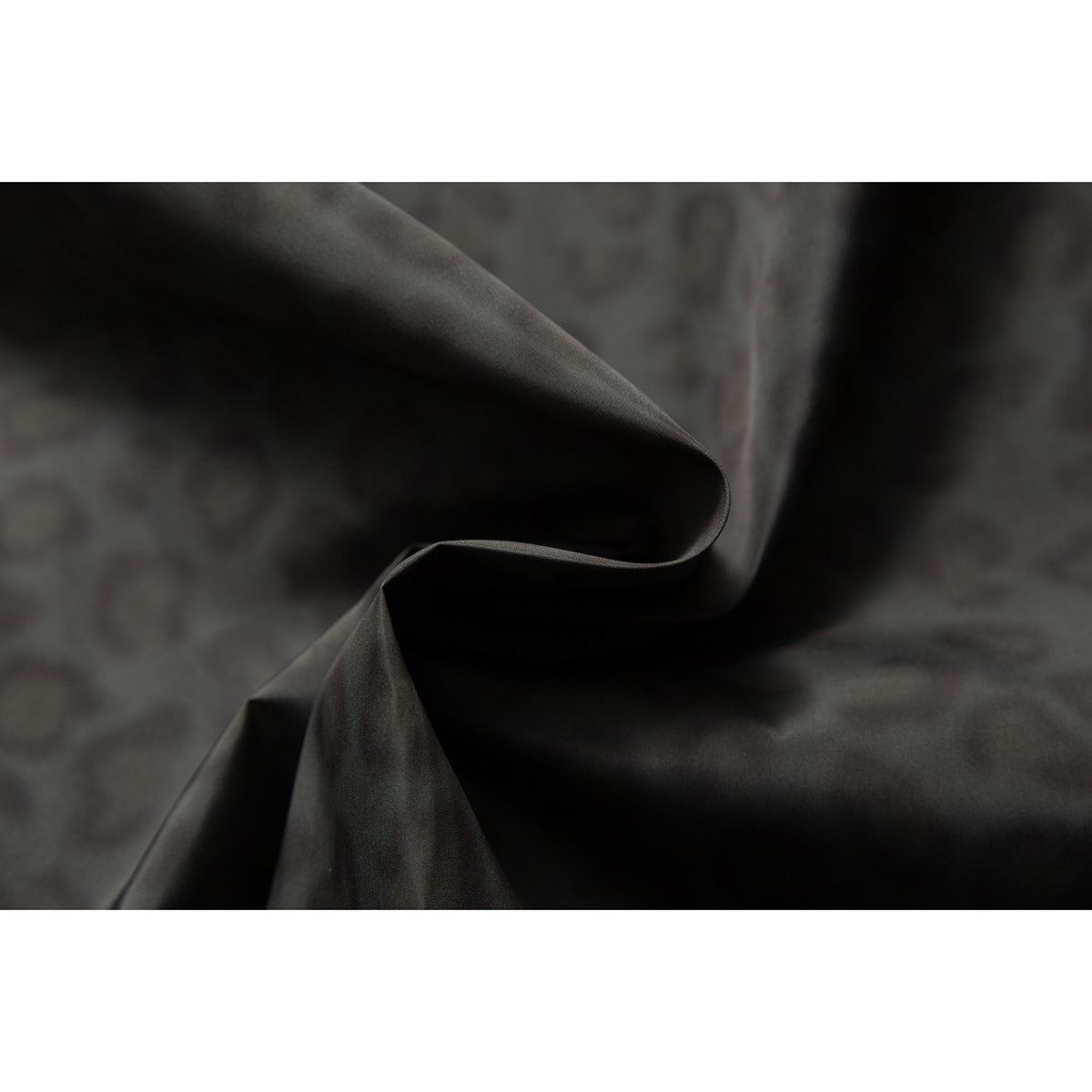 Dark patterned jacket fabric folded to show its drape and subtle mottled animal print.