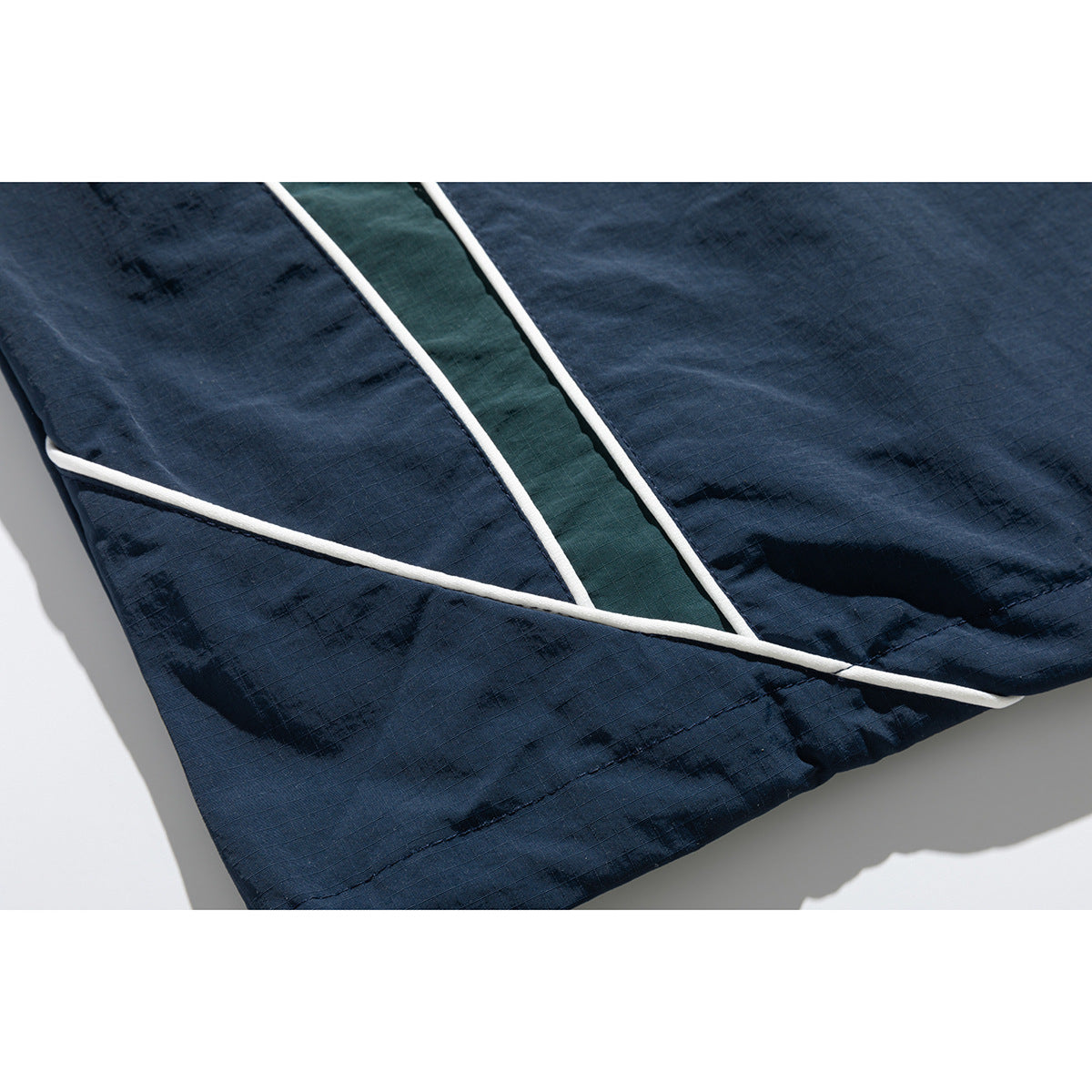Close-up of a navy jacket hem with white piping and a dark green inset panel.