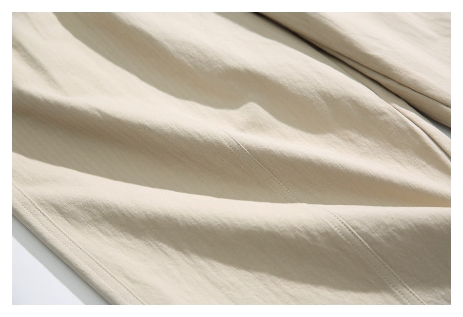 Close-up of beige pants fabric with stitched seams and a folded leg section.
