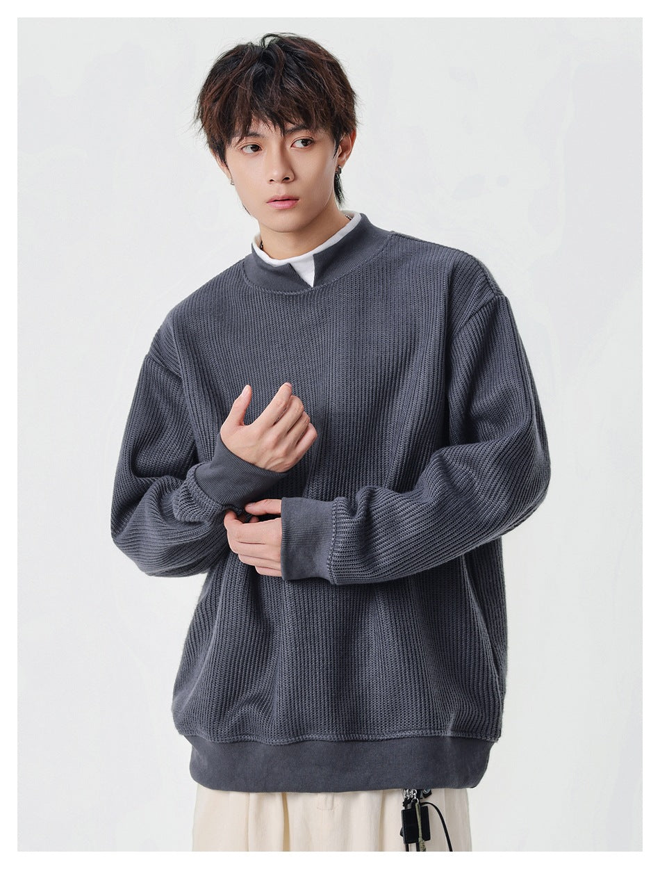 Model wearing a charcoal textured knit pullover with a split stand collar and ribbed trim.