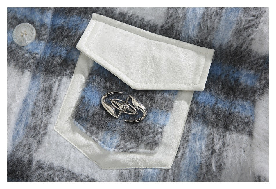 Close-up of a white-trimmed flap pocket with a metal emblem on the jacket's blue, gray, and white plaid fabric.
