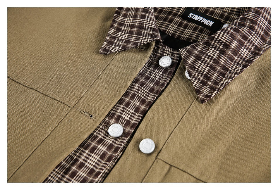 Close-up of a khaki overshirt showing its brown plaid placket and collar, chest pocket, and silver-tone buttons.