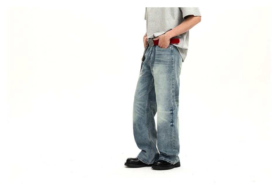 Side view of a model wearing loose light-wash blue jeans, a gray T-shirt and red belt.