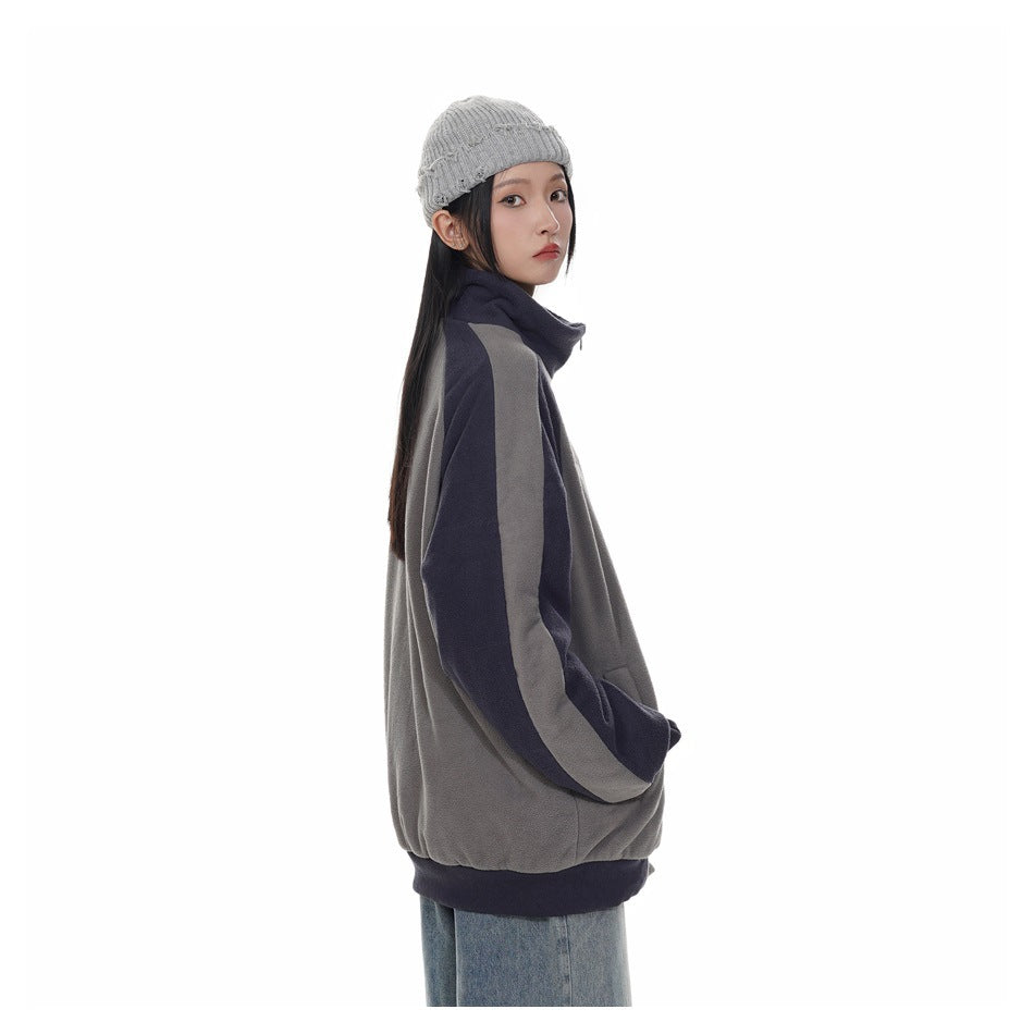 Side view of a person wearing the gray and navy color-block zip jacket with a gray knit beanie and jeans