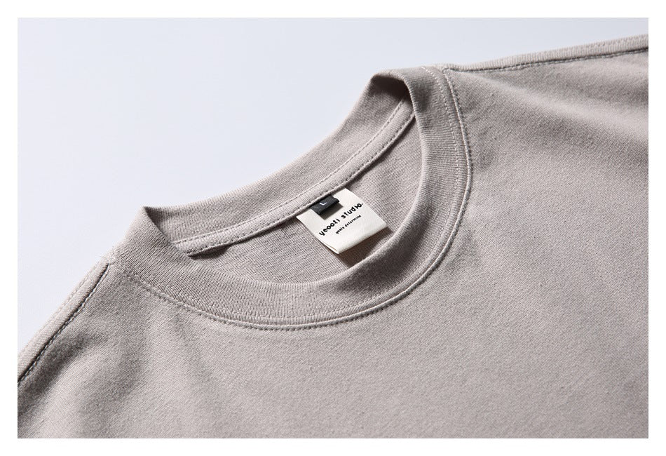 Close-up of a light taupe T-shirt's ribbed crew neck and sewn-in neck label.