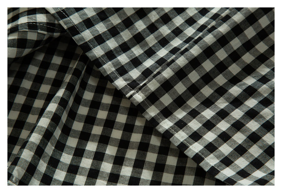 Close-up of overlapping black-and-white gingham shirt panels and stitching.