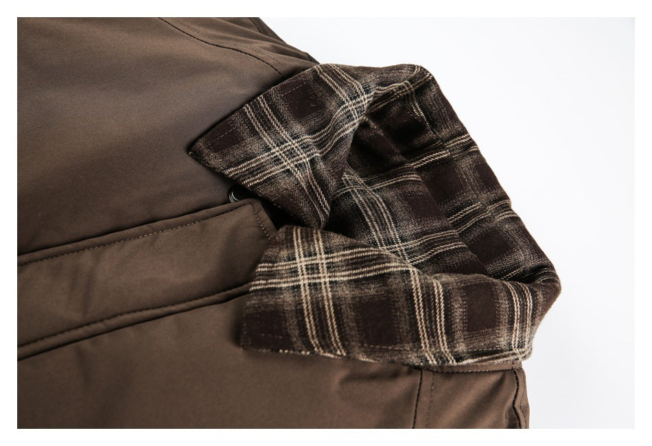 Close-up of a brown jacket's plaid collar and angled front pocket.