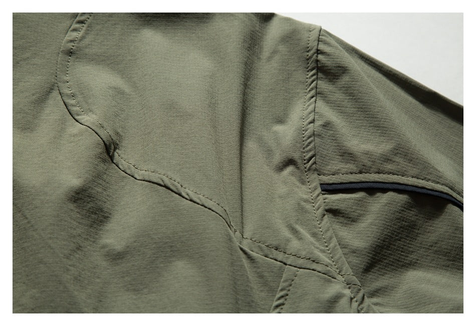Close-up of a curved stitched seam and dark piping on an olive-green garment.