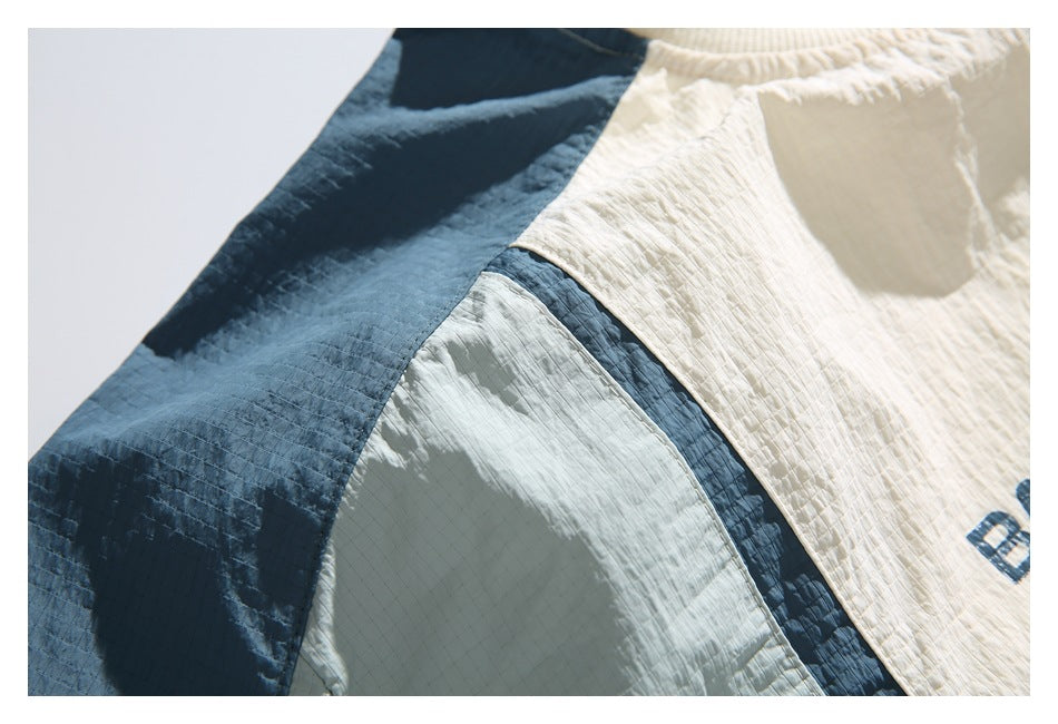 Close-up of a cream-and-blue color-block garment showing the shoulder seam and textured fabric.