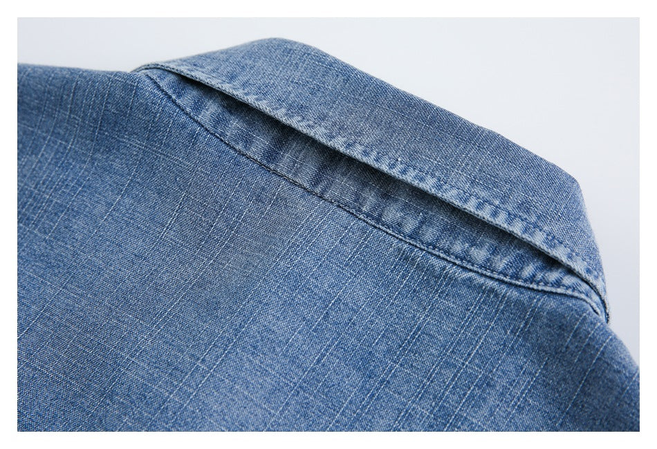 Close-up of the collar and shoulder seam on a blue denim shirt.