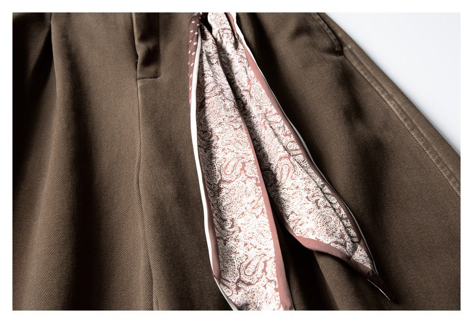 Close-up of dark brown trousers opened to show pale pink paisley-patterned inner fabric.