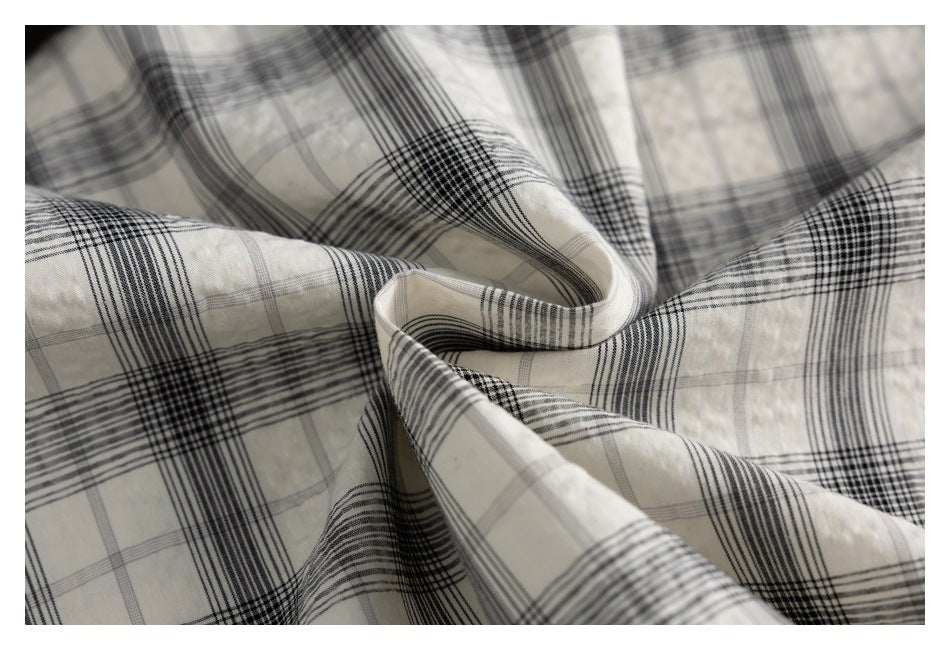 Close-up of draped white fabric with a black and gray plaid pattern.
