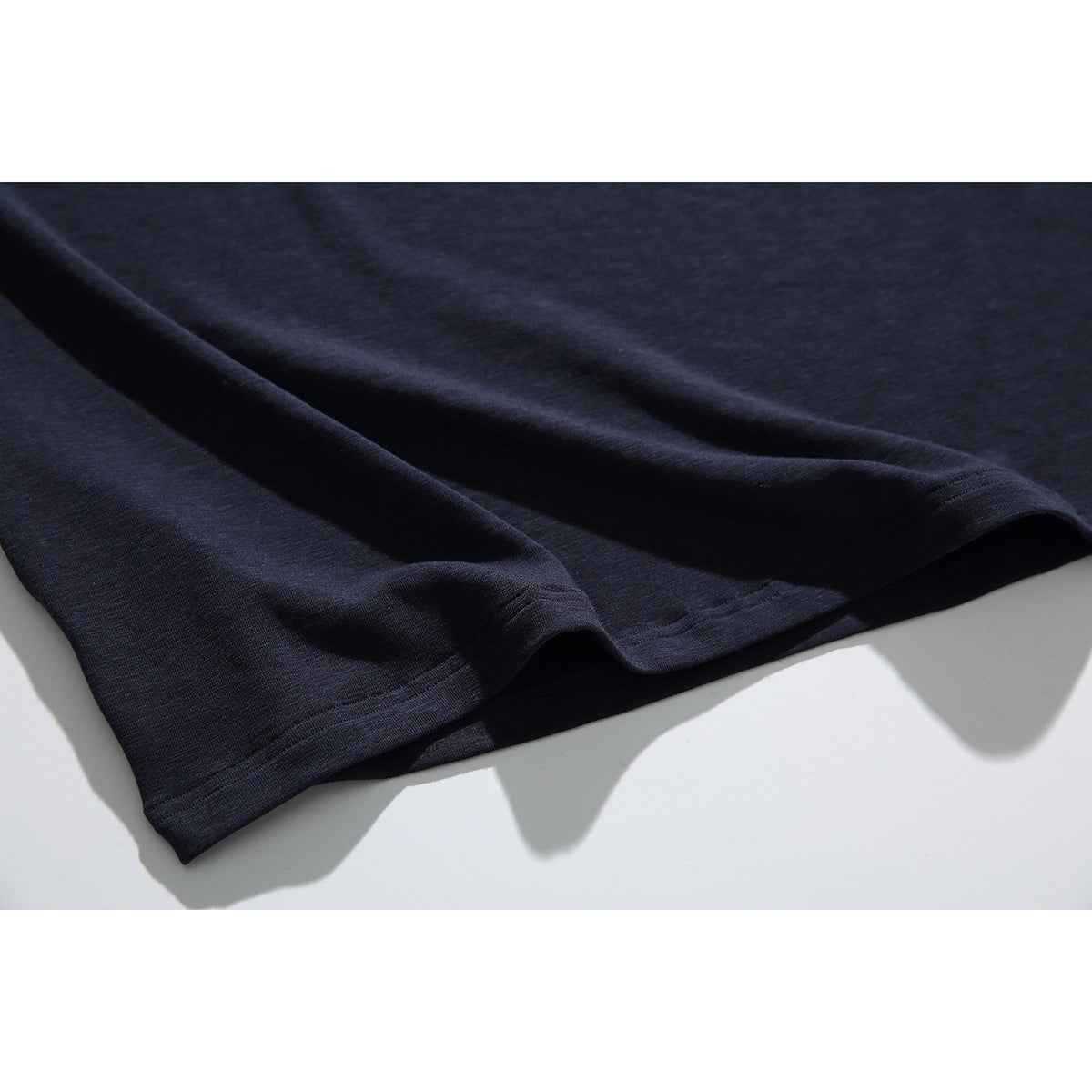 Close-up of the dark navy T-shirt fabric and double-stitched lower hem.