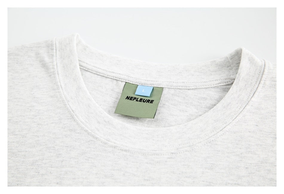 Close-up of a light gray crew neck and inner label marked NEPLEURE, size L.