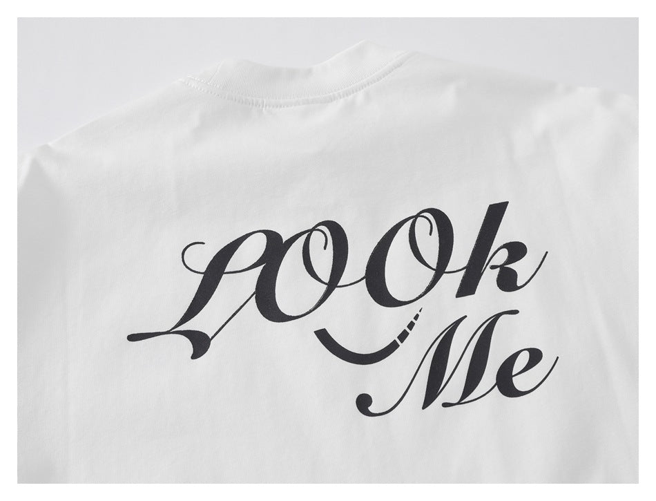 Back of a white T-shirt with large black script reading “Look Me.”