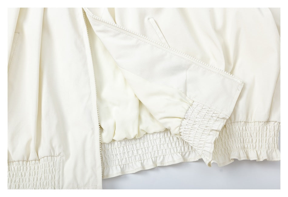 Close-up of an ivory garment showing overlapping panels and elastic-shirred ruffled edges.