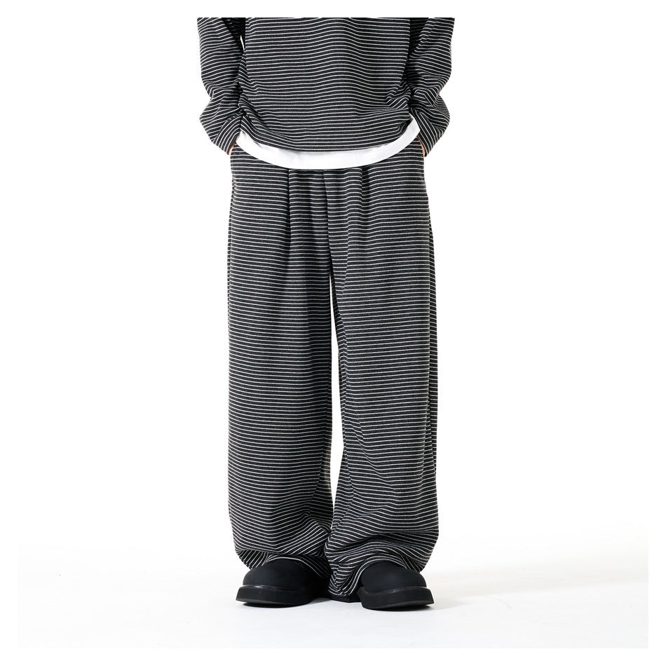 Front view of a model wearing loose black trousers with fine white stripes and a matching striped top.