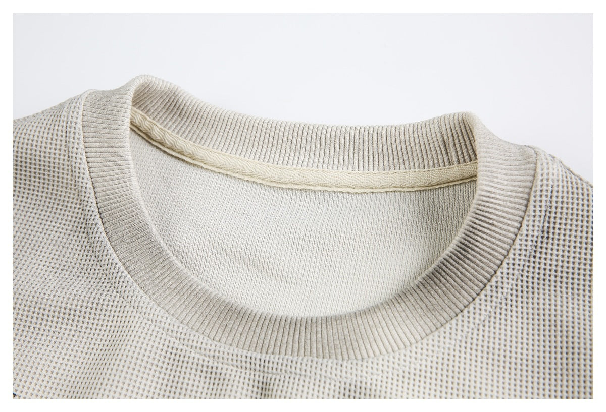 Close-up of a cream textured knit top's ribbed crew neckline and inner neck finish.