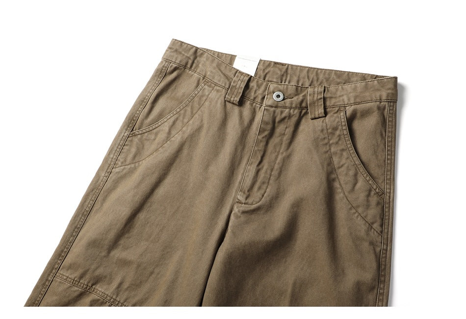 Cropped front view of khaki-brown pants showing the button closure, belt loops, and curved front pockets.