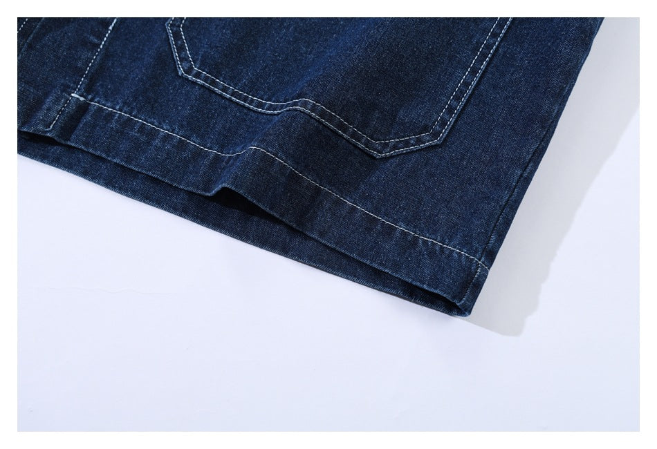 Close-up of a dark indigo denim garment's patch pocket and stitched hem.
