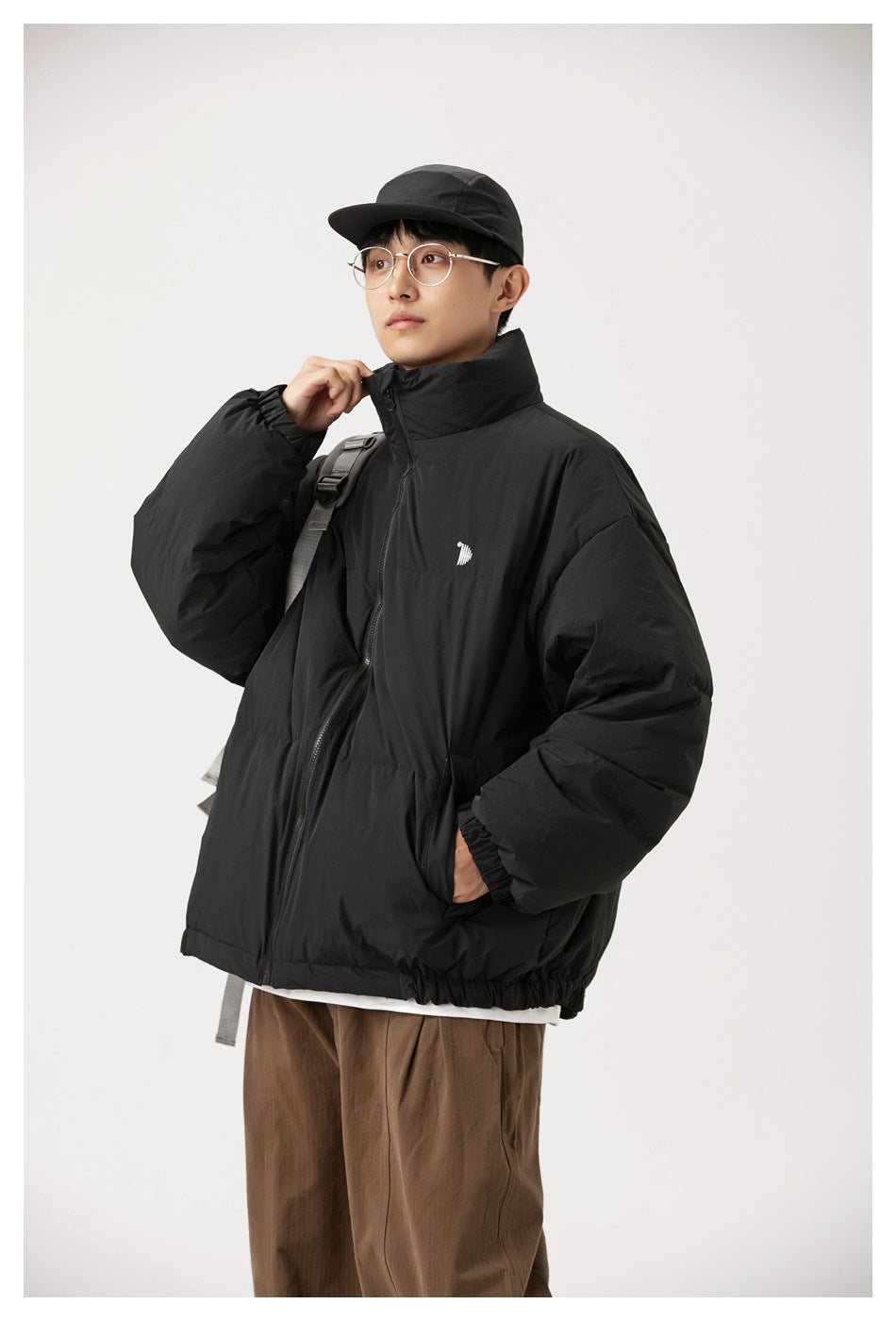 Angled front view of a person wearing a black padded jacket with a high collar and gathered cuffs.