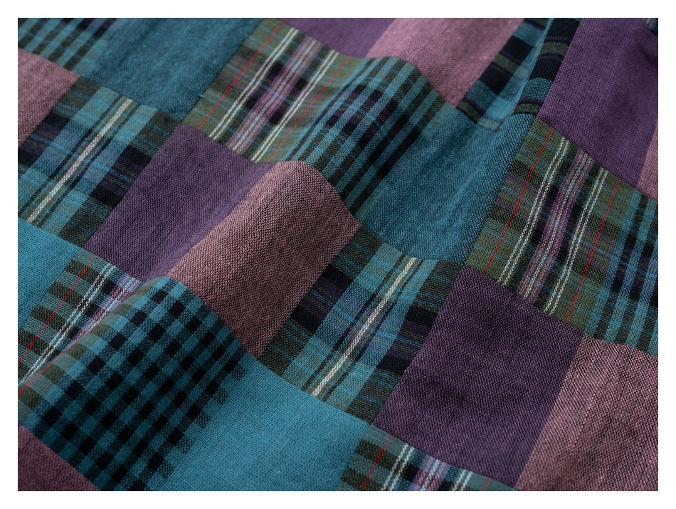 Close-up of teal, purple, and muted pink fabric with a patchwork of plaid and check patterns.