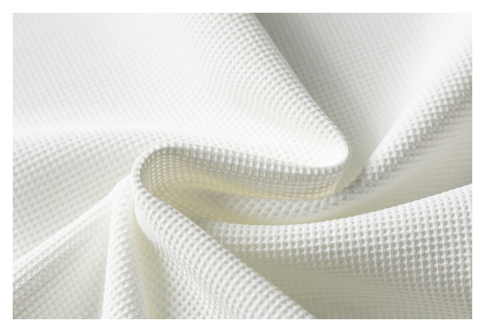 Close-up of softly folded white waffle-textured fabric.