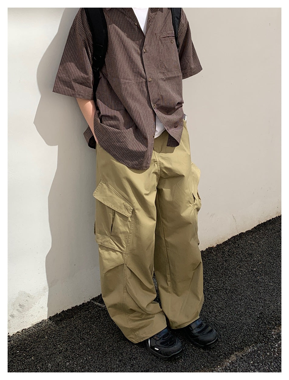 Model wearing loose tan cargo pants with large flap pockets, a striped shirt, and black shoes.