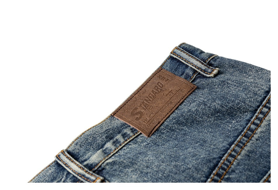 Close-up of a brown embossed patch and belt loop on the waistband of faded blue jeans.