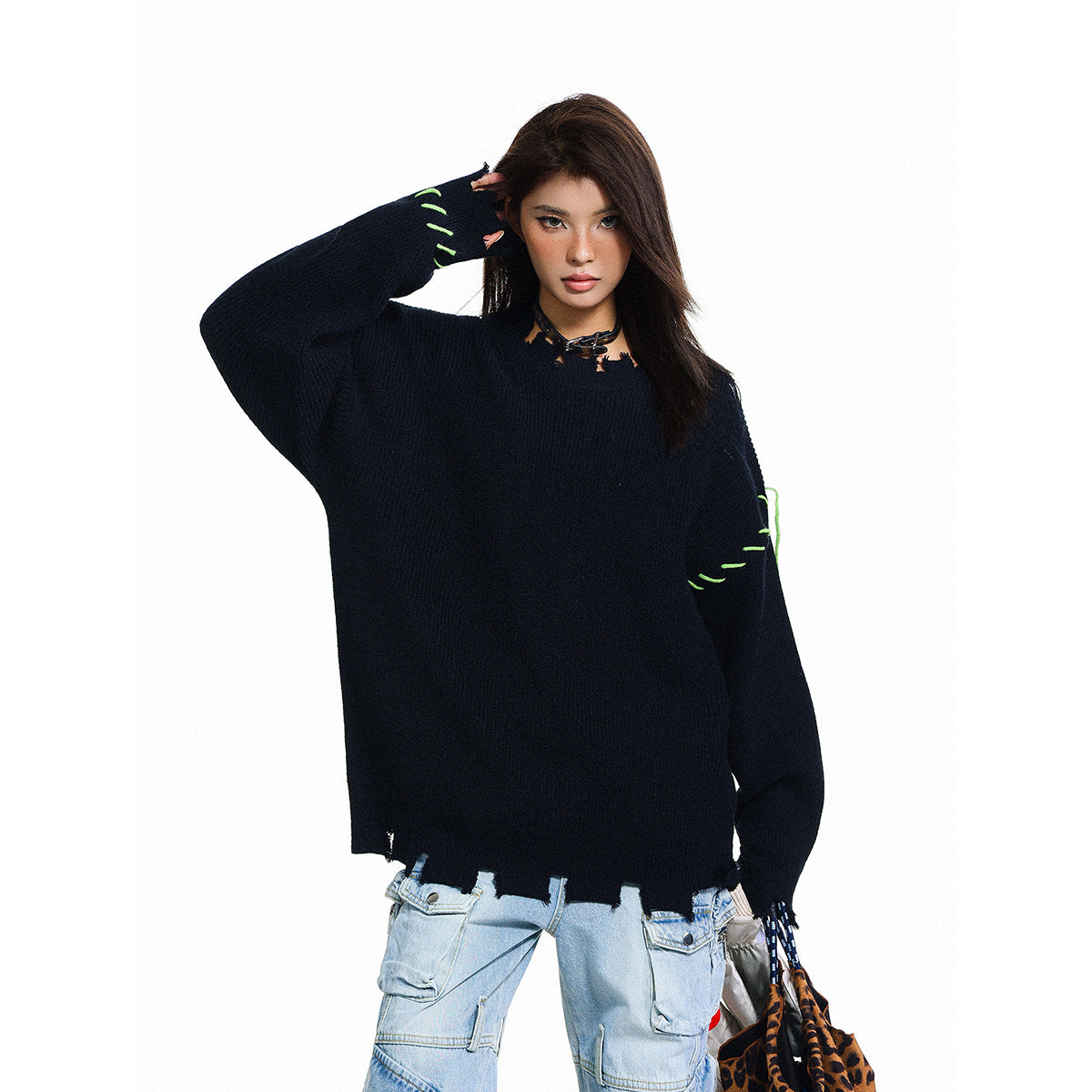 Model wearing an oversized black sweater with neon-green stitch accents and a distressed hem.
