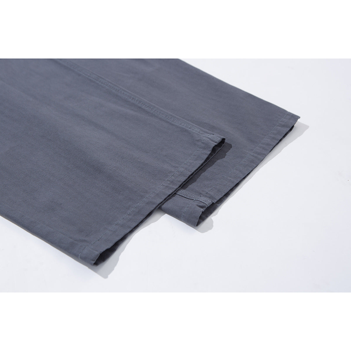 Close-up of charcoal gray trouser legs showing the straight stitched hems and wide-leg cut.