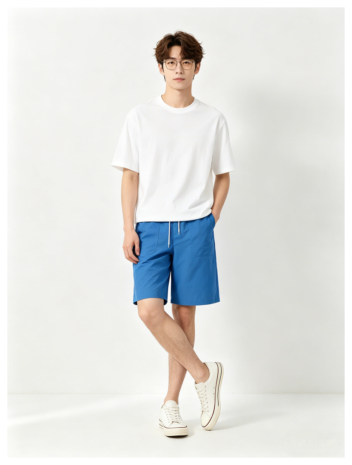 Model wearing a white crew-neck T-shirt with bright blue drawstring shorts and white sneakers.