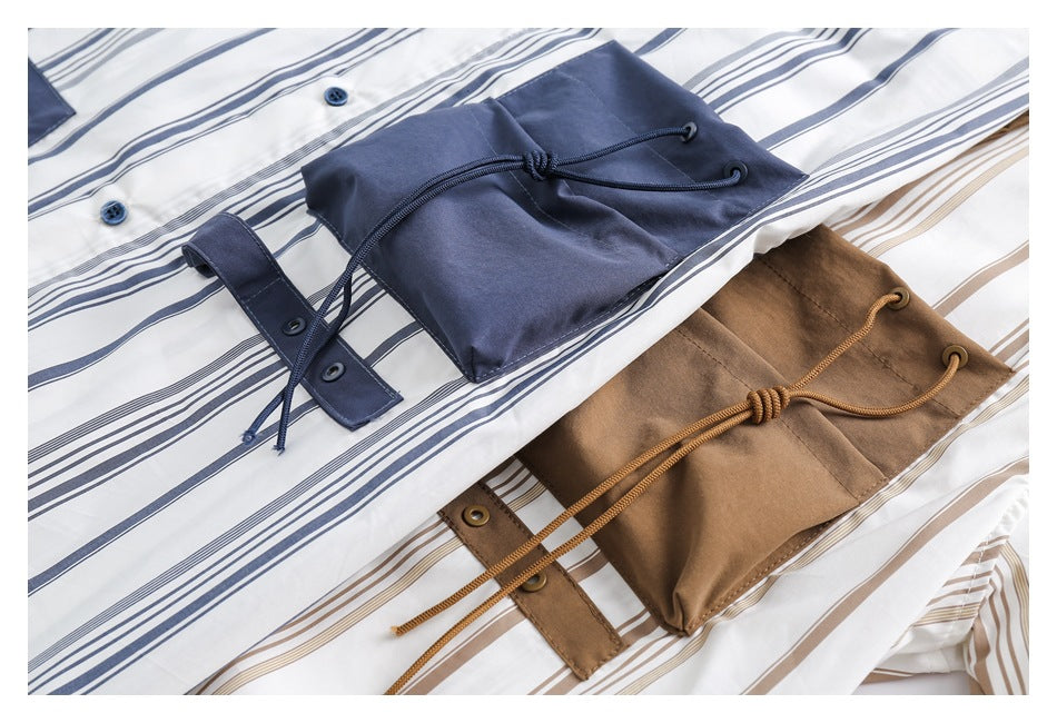 Close-up of navy and tan drawstring pockets on white striped shirts, with the navy pocket in front.