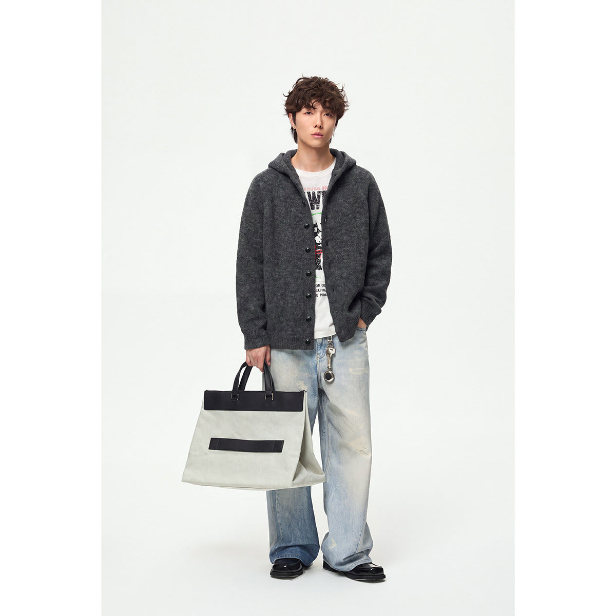 Full-length model wearing a charcoal hooded button-front cardigan with light jeans and carrying a large tote bag.