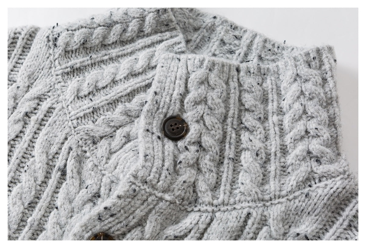 Close-up of a dark button on a light gray flecked cable-knit sweater.