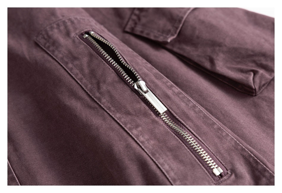Close-up of a silver diagonal zipper pocket on a muted plum garment.