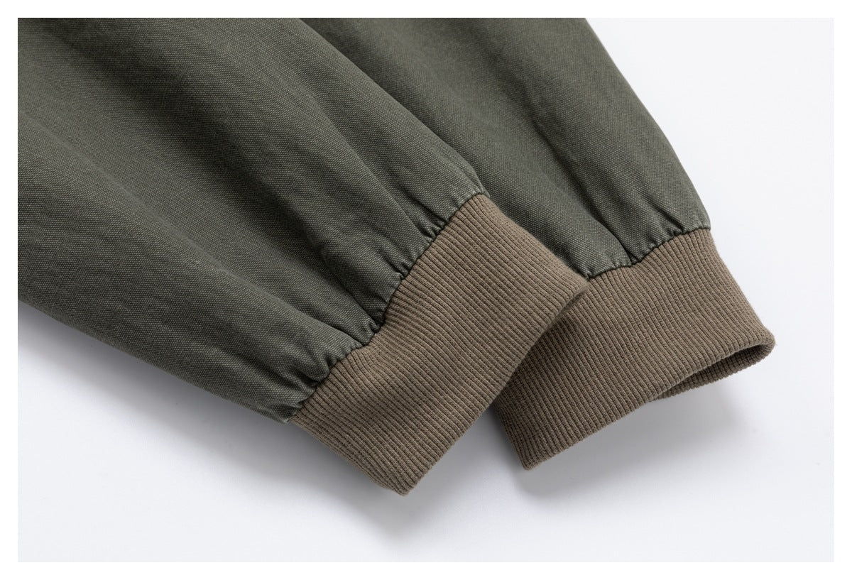 Close-up of olive-gray jacket sleeves ending in wide taupe rib-knit cuffs.