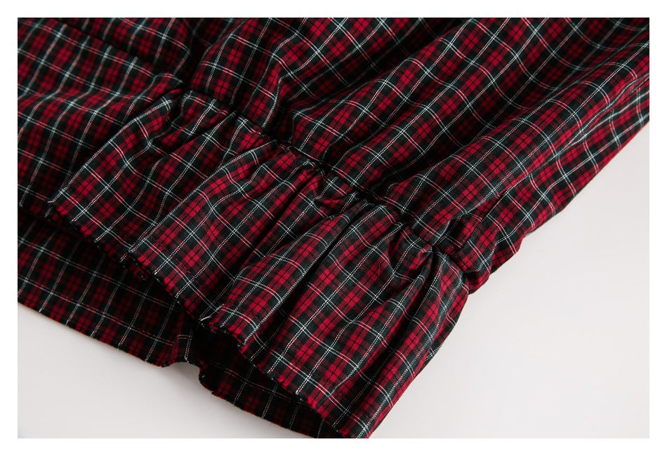 Close-up of gathered, layered fabric on a red, black, and white plaid garment.