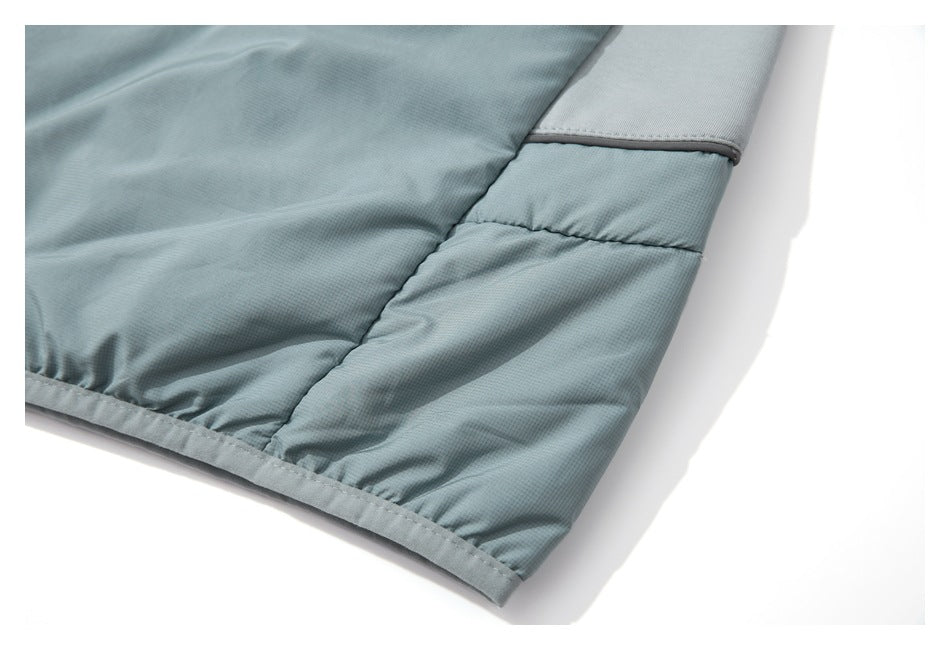 Close-up of pale blue-gray garment hem and side panel with a contrasting fabric section and trim.