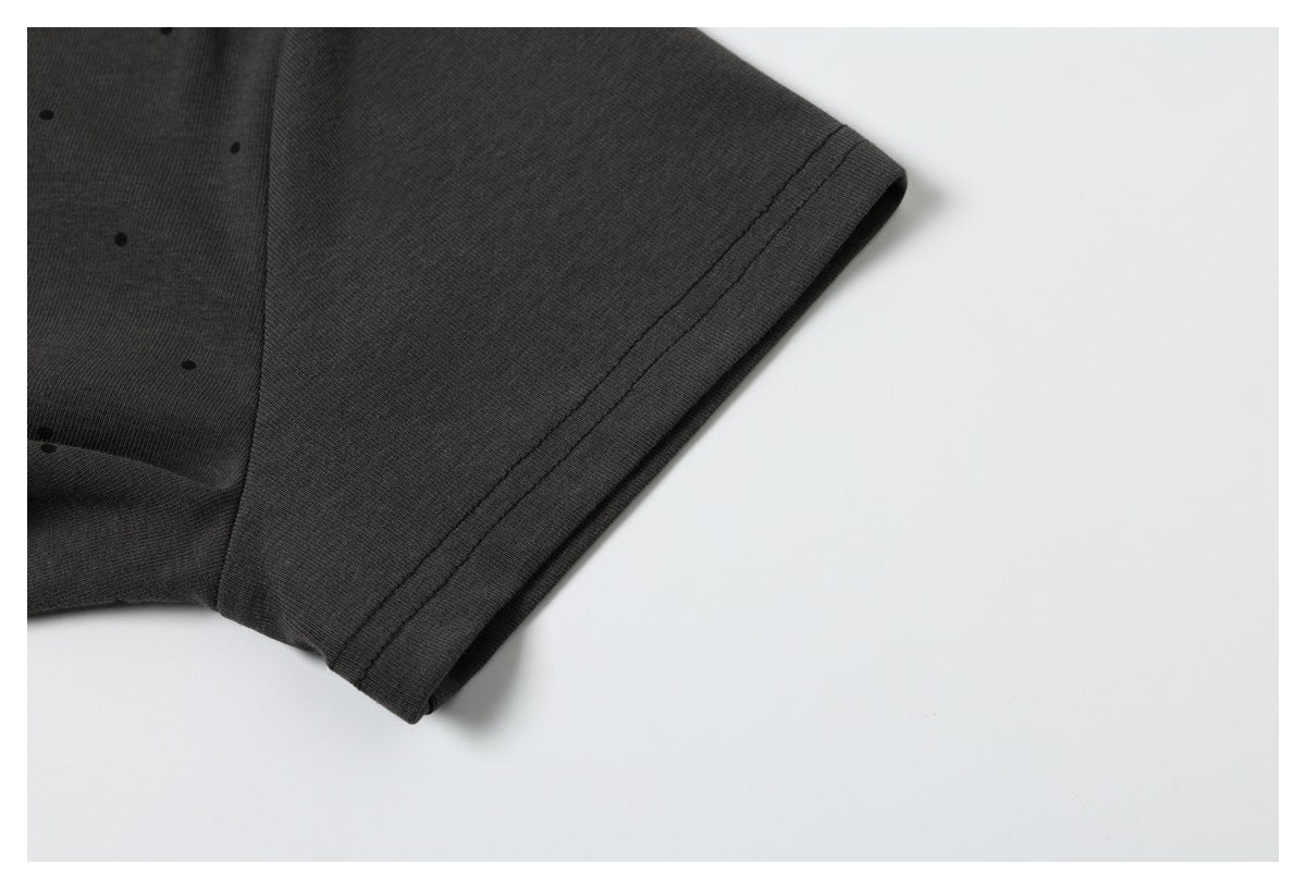 Close-up of the charcoal T-shirt's short sleeve and stitched hem, with small black dots on the fabric.